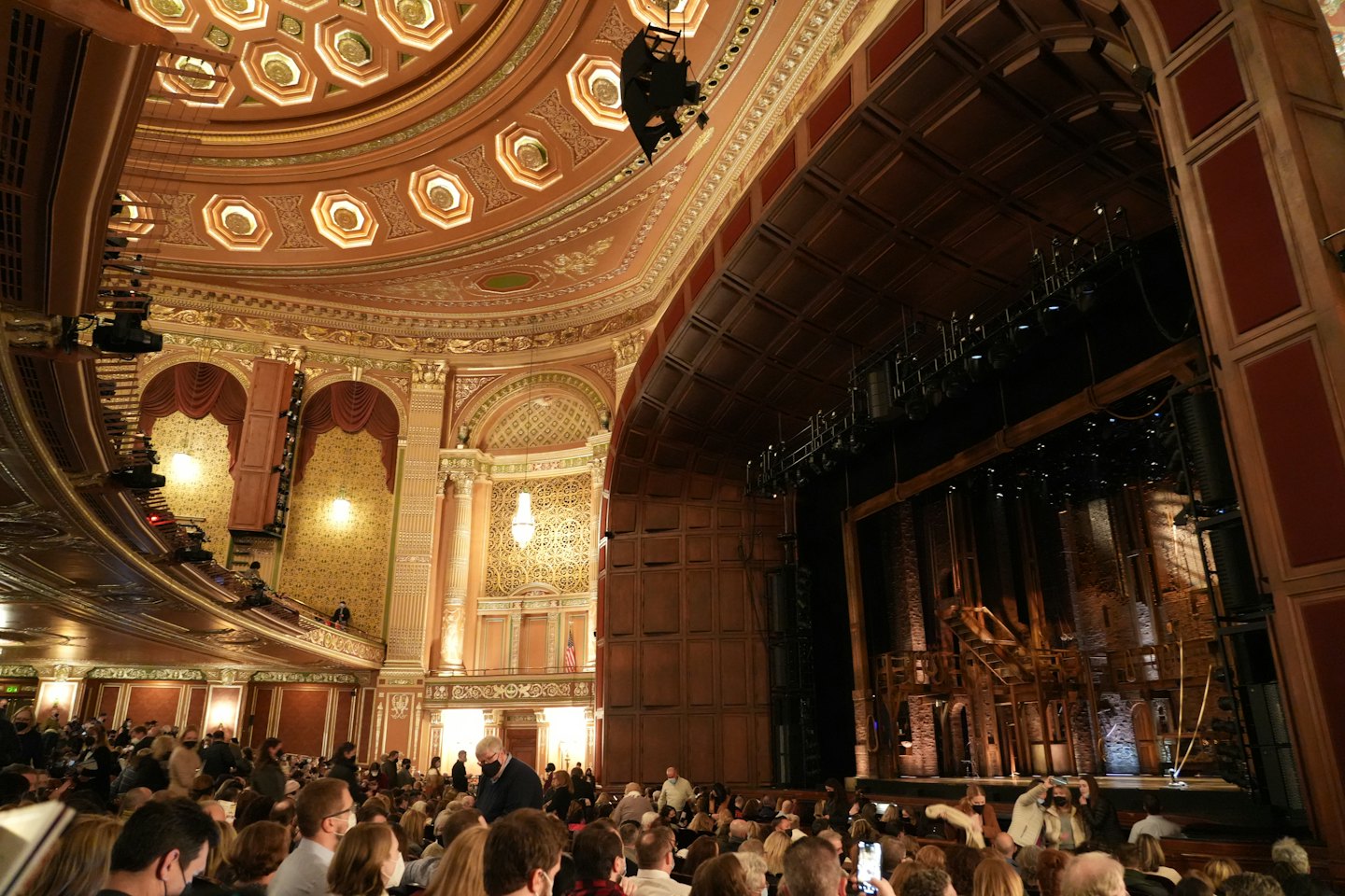Un pubblico siede in un grande teatro a guardare uno spettacolo sul palco.