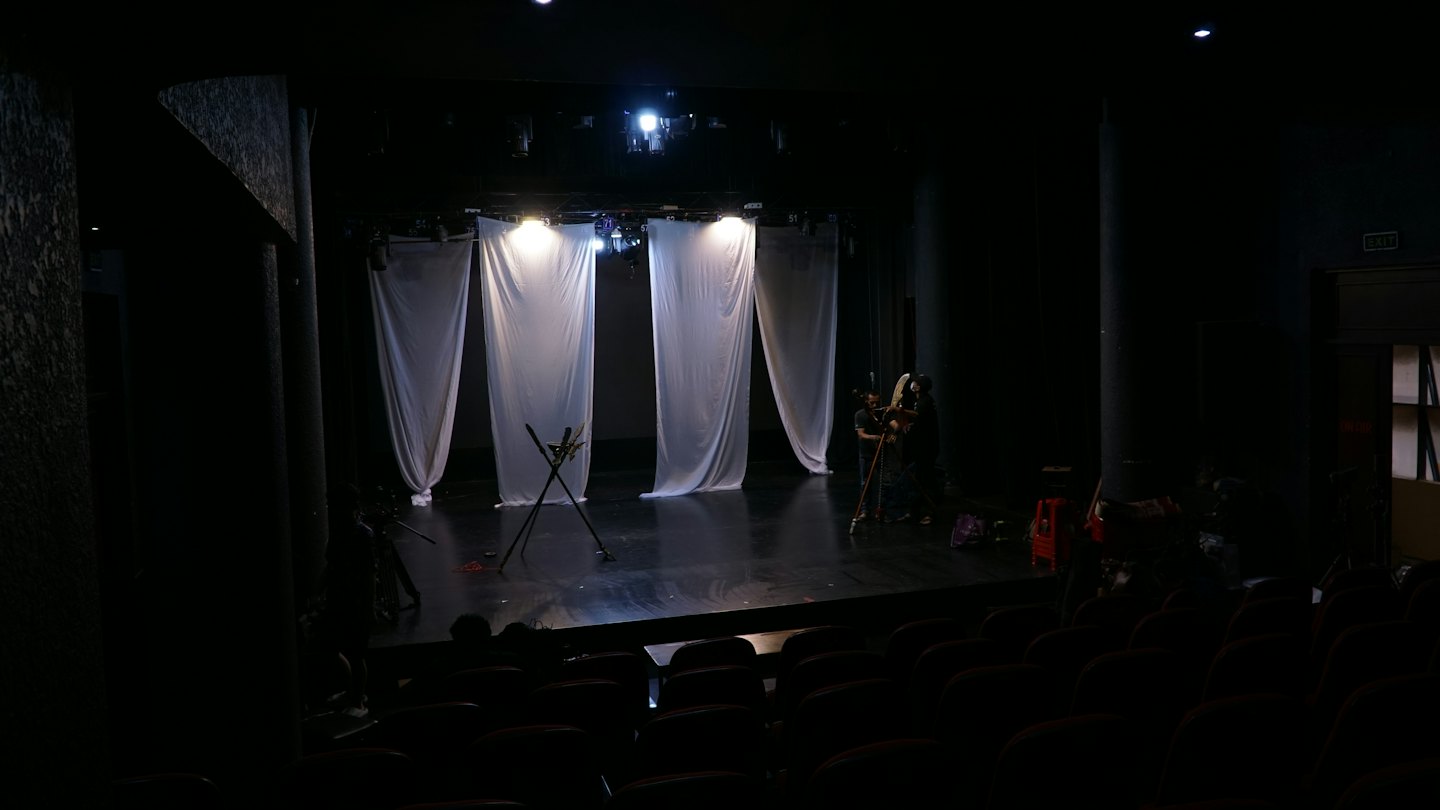 Membri della troupe teatrale che preparano la scenografia su un palcoscenico.