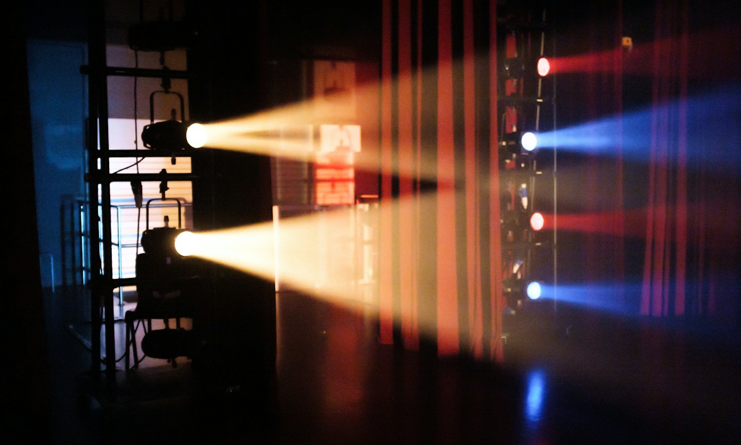 I riflettori del palco proiettano fasci di luce vibranti su uno spazio buio per le esibizioni.