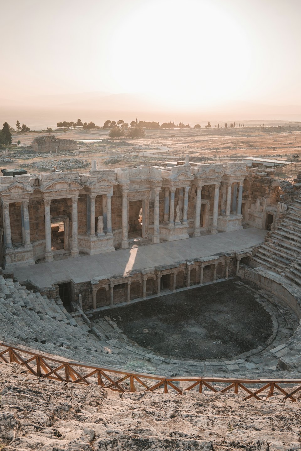 Rovine di un antico teatro romano con posti a sedere in pietra e colonne ornate.
